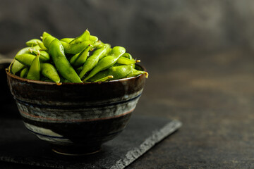 Canvas Print - Green edamame pods. Fresh soybeans in bowl on black table.