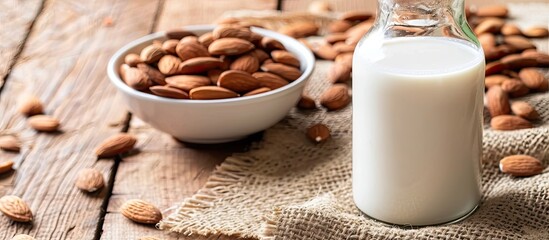 Poster - A bowl with almonds sits next to a glass bottle of almond milk on a table with a blank area for additional content in the image