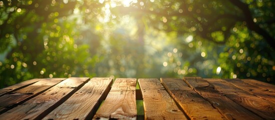 Poster - Morning sunlight and green bokeh illuminate a wooden table with space for product display set against a blurred natural backdrop. with copy space image. Place for adding text or design