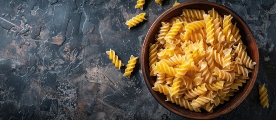 Poster - Top view of uncooked Creste di Gallo pasta presented in a wooden bowl on a dark vintage backdrop with room for text or other graphics in the image. with copy space image