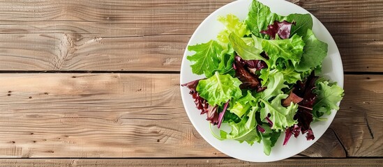Fototapete - Top view of a salad with crisp lettuce leaves in a white plate on a wooden table background featuring copy space image