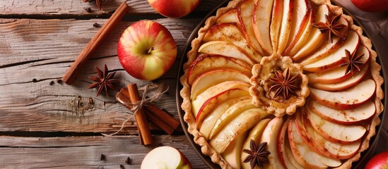 Leinwandbilder - Close up top view of a homemade fruit tart with golden crust featuring whole and halved apples cinnamon sticks and anise seeds against a background with copy space image