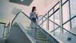 © Suriyawut - A business woman is walking down to escalator with a coffee cup in her hand