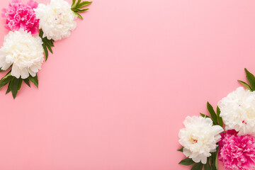 Wall Mural - Fresh beautiful soft white pink peony flowers with green leaves on pink table background. Pastel color. Closeup. Empty place for inspirational text, lovely quote or positive sayings. Top down view.