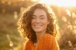 © furyon - carefree woman with cascading curly brown hair warm orange knit sweater genuine smile radiating joy natural outdoor setting golden hour lighting enhancing warm tones