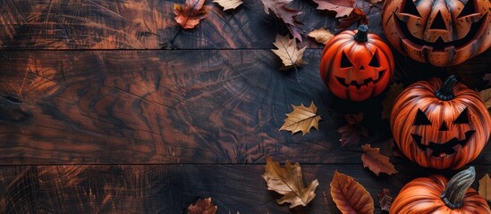 Poster - A flat lay image of Halloween pumpkins autumn leaves on a wooden table with space for text. copy space available