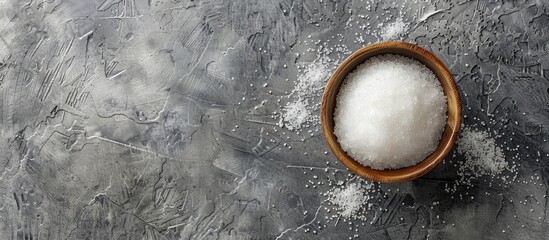 Poster - Top view of a bowl with granulated sugar on a textured grey table providing ample space for text in the image