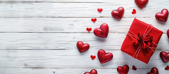 Poster - Red toy hearts and a gift box for Valentine s Day arranged on a white wooden table with a top down view and space for adding images. copy space available