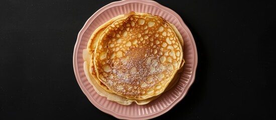 Poster - Top view of a homemade apple Dutch pannekoek pancake served on a pink plate against a black backdrop captured as a flat lay image with copy space available