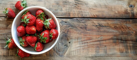 Poster - A top view copy space image features fresh strawberries in a white bowl on a rustic wooden table