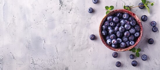 Poster - Top view of a bowl filled with blueberries on a wooden surface against a white concrete background with copy space image