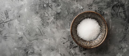Poster - Top view of a bowl with granulated sugar on a textured grey table providing ample space for text in the image