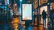 © Fitriyani - Mockup. Blank white vertical advertising poster billboard standing in city at night. Digital screen display light box for advertising or information on modern city street.