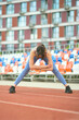 © yavdat - woman in blue sports gear performs an arm stretch on a sunny track. This photo aligns with modern fitness trends that advocate for comprehensive warm-up routines to enhance workout efficiency.