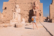 © muratart - A beautiful young girl in shorts is standing examining historical artifacts - Ancient Temple of Karnak in Luxor - Ruined Thebes Egypt