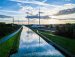 © Bjorn B - A canal with turbines reflects peace and natures beauty under a vibrant sunset in a tranquil evening