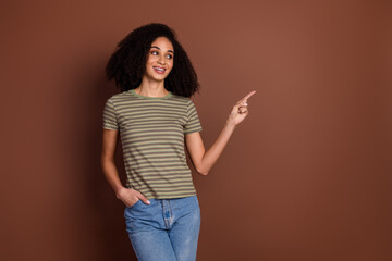 Poster - Photo of charming positive girl wear striped t-shirt smiling showing empty space isolated brown color background