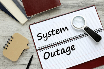 System Outage text on a white page of a diary on the table