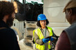 © Marko Geber - Female logistics manager with clipboard discussing with truck drivers