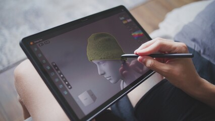 Fototapete - Boy with digital stylus and tablet in hands sits at home, creates 3d models. Focused teenager draws clothes for game character using 3d modeling program. Development and game design concept. Close up.