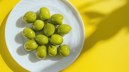 Wall Mural - Fresh green olives on white plate with yellow backdrop