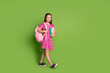 © deagreez - Full size photo of cute schoolgirl walk empty space wear pink dress isolated on green color background