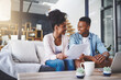 © peopleimages.com - Budget, laptop and couple with documents on sofa for bills, life insurance or mortgage. Lens flare, paperwork and black man with woman on computer for planning finances, payment or investment in home