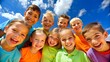 © Rudsaphon - Group of cheerful children smiling and laughing outdoors under a bright blue sky, enjoying a fun and joyful day together.