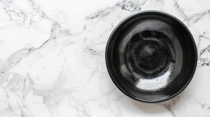 Top view of black bowl on white marble table with water text space available