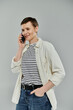 © LIGHTFIELD STUDIOS - A woman with short hair, wearing a white shirt over a striped tee and jeans, smiles as she talks on her phone.