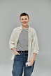 © LIGHTFIELD STUDIOS - A woman with short hair, dressed in casual clothing, stands confidently against a gray background.