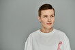 © LIGHTFIELD STUDIOS - A woman with short brown hair wears a white shirt with a pink ribbon, symbolizing her support for breast cancer awareness.