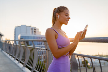 Wall Mural - attractive young woman doing sports in the morning using smartphone