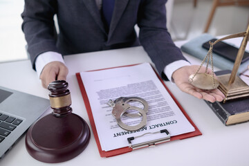 Handcuffs and legal documents were placed on table inside lawyer office after court decision was announced. legal counsel On desk documents and handcuffs were placed after court fought and won case.