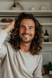 © Jasmina - Portrait of happy young attractive man with long curly hair at home