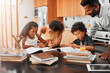 © BestLens/peopleimages.com - Family, children and books with homework for learning, guidance or help on kitchen table. Mother, father and young kids studying together for education, knowledge or childhood development at house