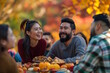 © MarGa - Group of friends having a thanksgiving picnic in a park surrounded by fall foliage. Concept of thanksgiving, friendsgiving, and outdoor celebration