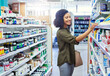 © TamJam/peopleimages.com - Medication, healthcare and woman in pharmacy for shopping with purchase for medical treatment supplies. Medicine, pharmaceutical and female person looking for pills in retail drugstore chemist.