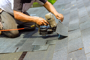 Wall Mural - During installation of new bitumen shingles, construction roofer used pneumatic air nail gun