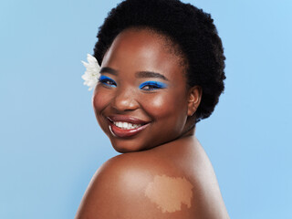 Wall Mural - Portrait, black woman and makeup in studio, flower and organic eyeshadow on blue background. Smile, mockup and cosmetics for glamour and female person, face and skincare for glow and birthmark