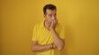 © Krakenimages.com - Hispanic man wearing a yellow shirt looking thoughtful against a yellow background, embodying a mature and handsome elderly demeanor.