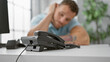 © Krakenimages.com - A young bearded man in a casual office setting, appears pensive as he rests his head on his hand near a phone.