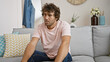 © Krakenimages.com - Handsome young hispanic man sitting thoughtfully in a modern living room interior.