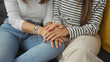 © Krakenimages.com - Two women seated closely on a couch, hands intertwined, expressing affection in a cozy living room.