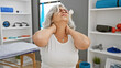 © Krakenimages.com - A mature woman experiences neck pain at a physical therapy clinic, signaling potential chiropractic needs.