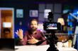 © DC Studio - Focus on professional recording equipment used by media star in blurry background to film vlog channel intro. Close up of camera used by man to record himself greeting fans