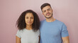 © Krakenimages.com - A multicultural couple stands together against a pink background, conveying love and unity.