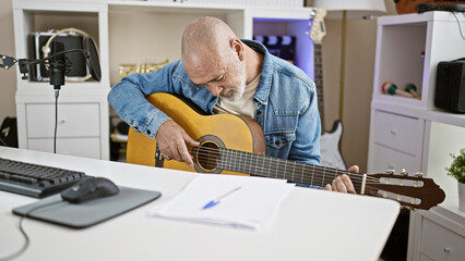 Wall Mural - Bald man playing acoustic guitar in a modern office with a microphone and computer desk.