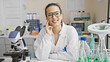 © Krakenimages.com - Smiling young hispanic woman scientist in laboratory with microscope and glassware
