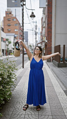 Wall Mural - Joyful hispanic woman in glasses embraces freedom in tokyo, open arms welcoming city charm, lost in street beauty looking around with wide smiles